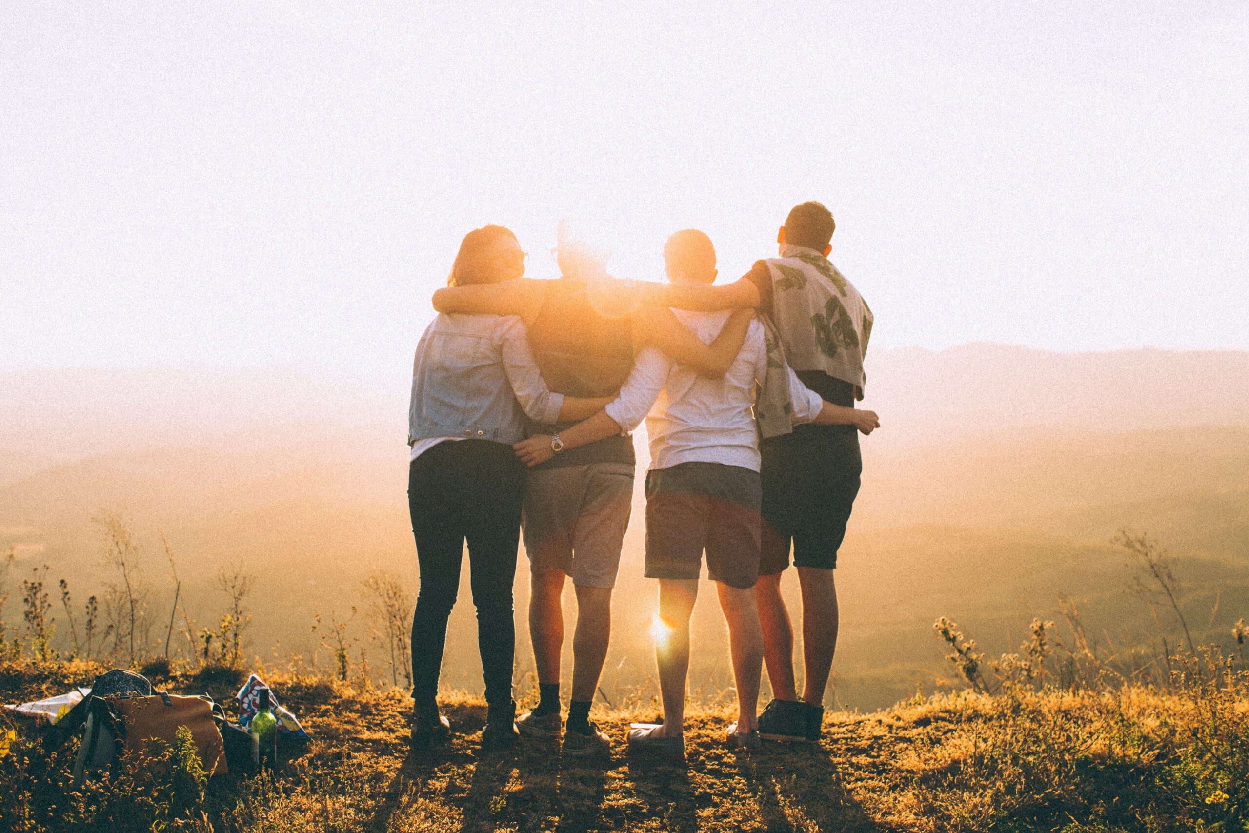 Parents embracing their teenage children outdoors at sunset-showing calm connection and emotional support.